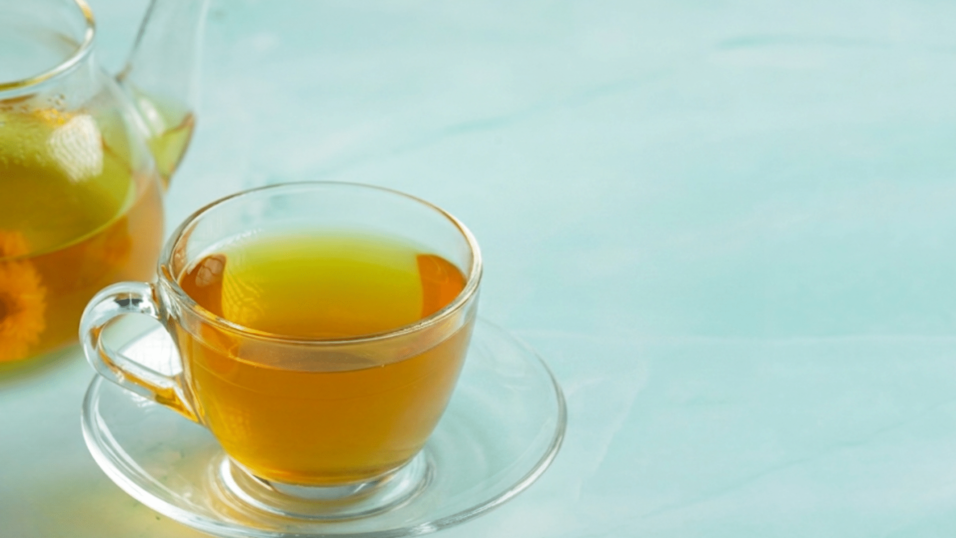 freshly brewed green tea in a clear glass cup with a matching glass teapot
