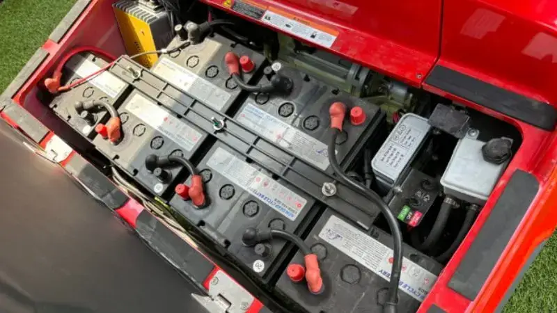 Electric golf cart battery pack with multiple connected cells and wiring in outdoor setting