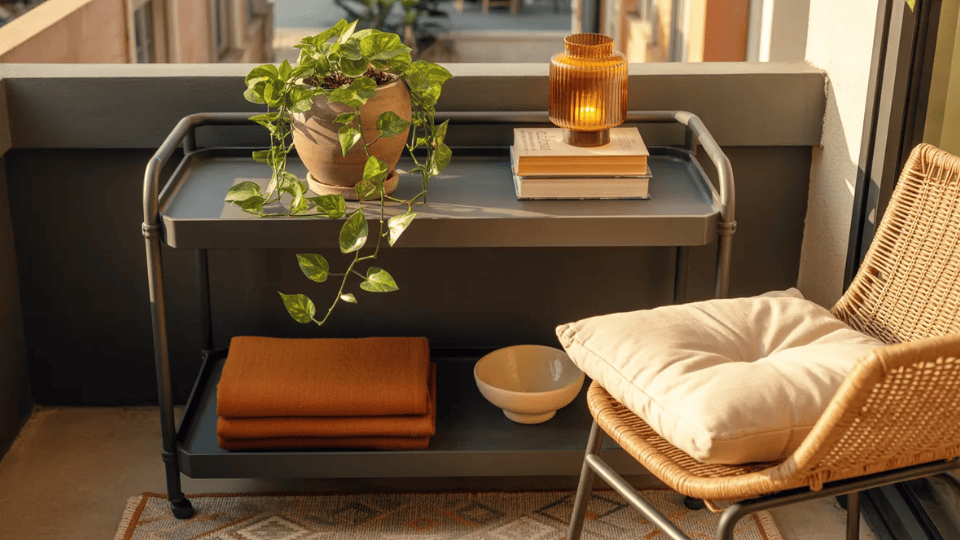 matte black bar cart on balcony with pothos amber lantern books rust throw beside rattan chair and patterned rug