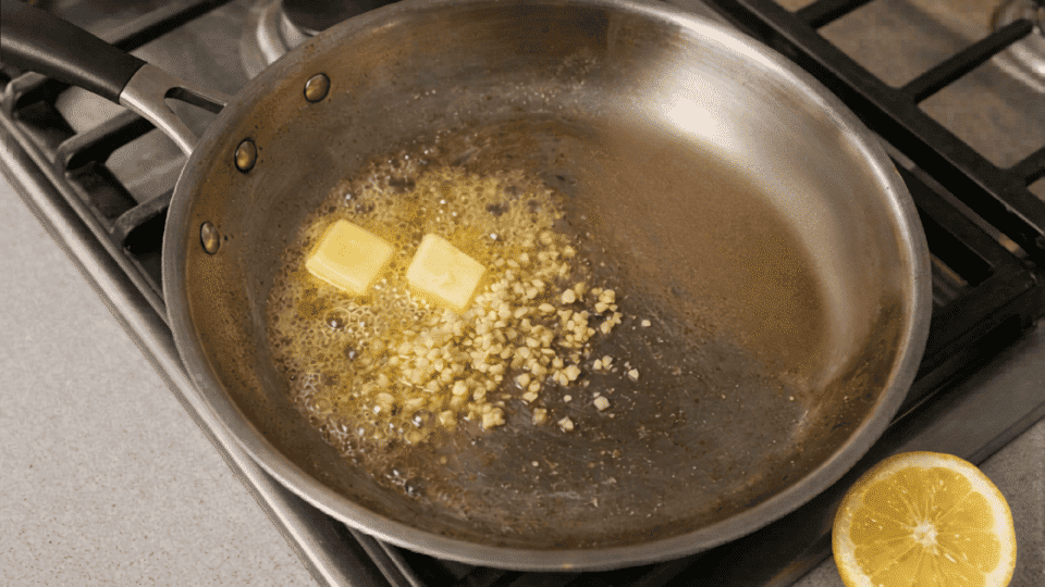 a pan with butter and garlic on slow heat being made into a smooth sauce for dressing fish