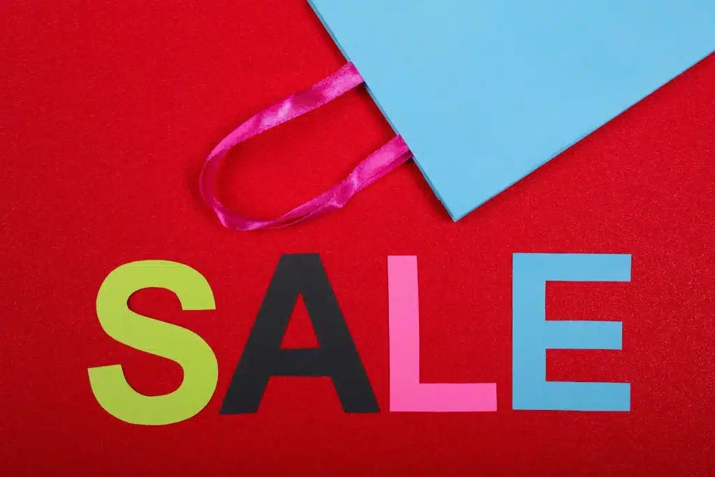 Colorful sale letters on red background with blue shopping bag