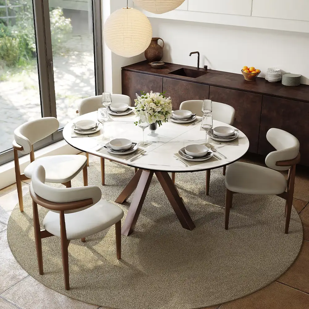 Modern dining setup with round marble table and white chairs in sunlit room