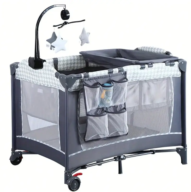 Gray and white portable baby crib with star mobile and storage pockets in nursery setting
