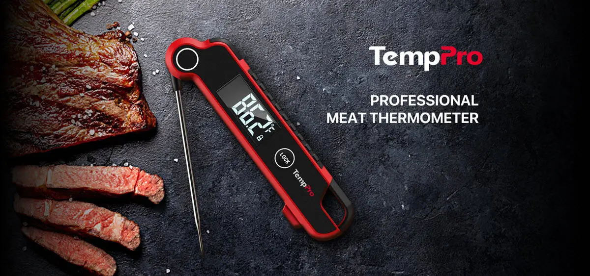 Digital meat thermometer with red accents next to slices of grilled steak on dark surface