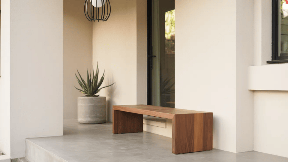 a minimalist front porch with neutral tones sleek bench and a single architectural plant in natural daylight