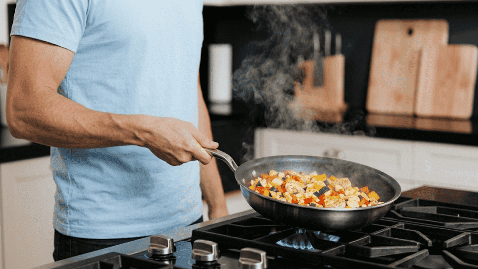 a picture showing the man cooking food in baby blue tshirt with minimal things