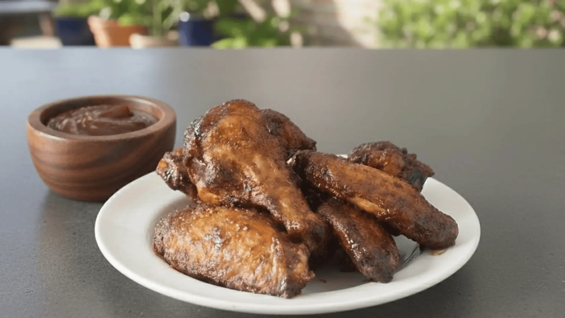 baked chicken wings arranged on white plate with light seasoning and dipping sauce, served in natural daylight kitchen environment setting