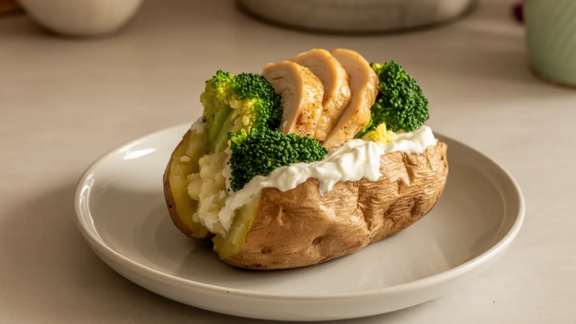 baked potato fully prepared with Greek yogurt, steamed broccoli, and grilled chicken on top, plated neatly, balanced meal look