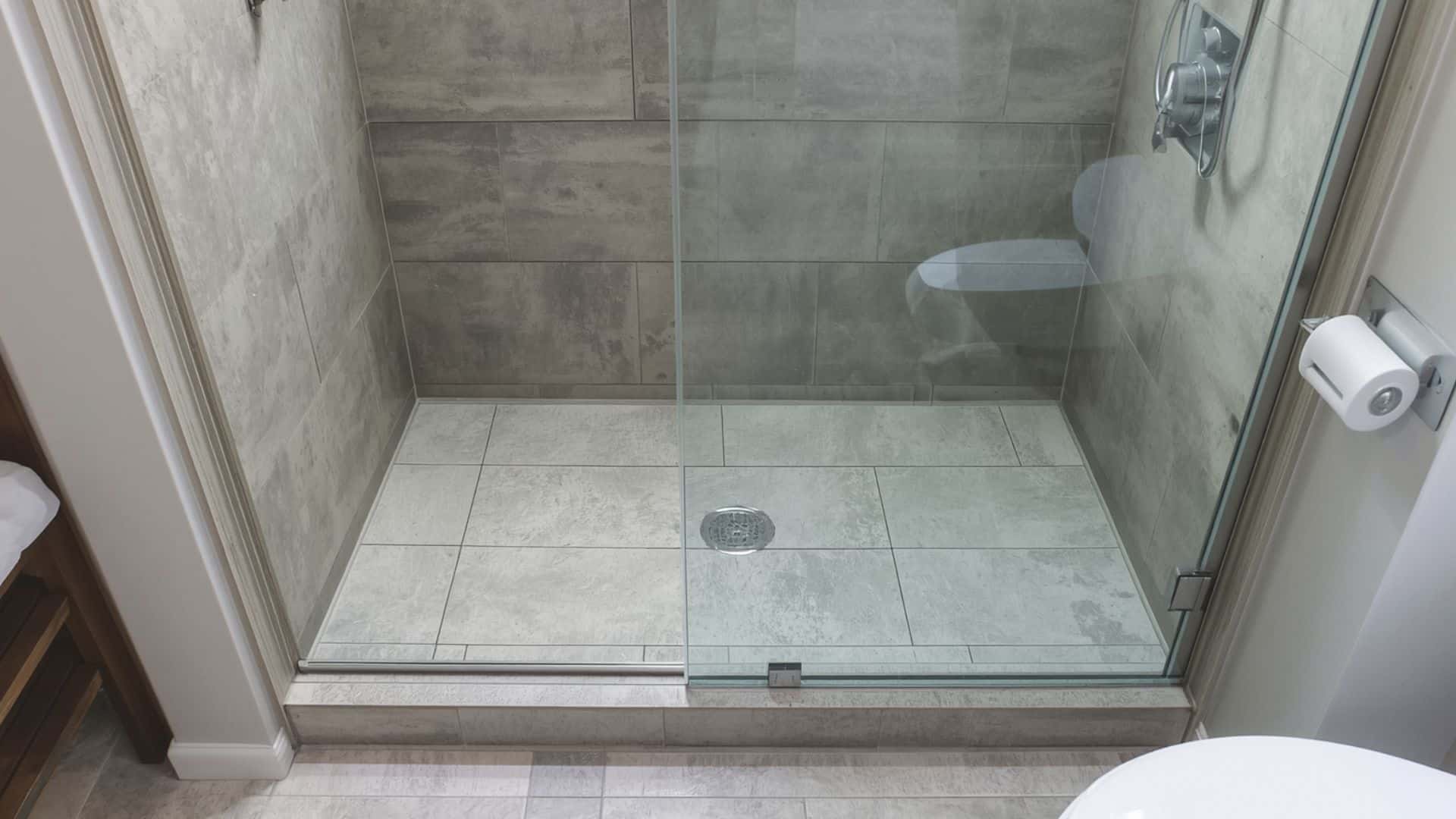 bathroom remodel with a curbless shower, seamless floor tile continuing into the shower area, linear drain, clear glass panel, modern accessible design