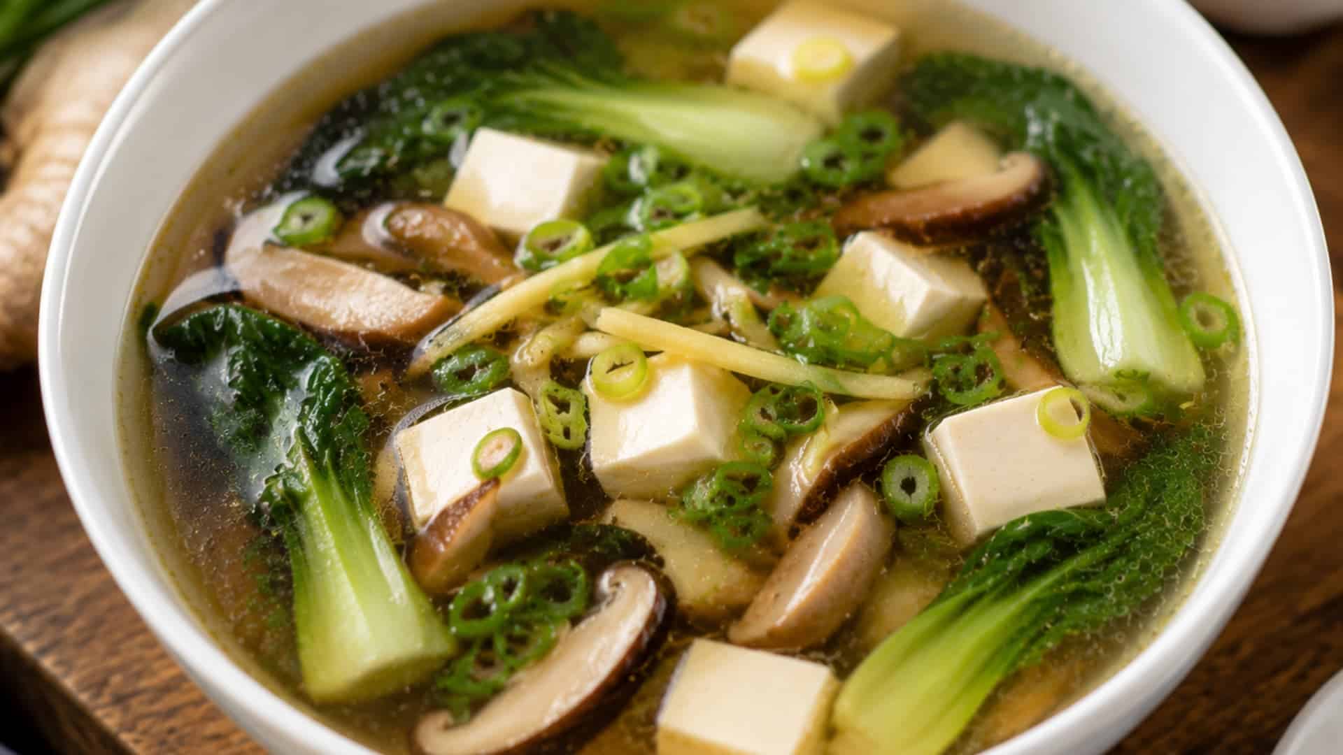 clear asian vegetable soup with tofu cubes mushrooms bok choy and scallions in light broth