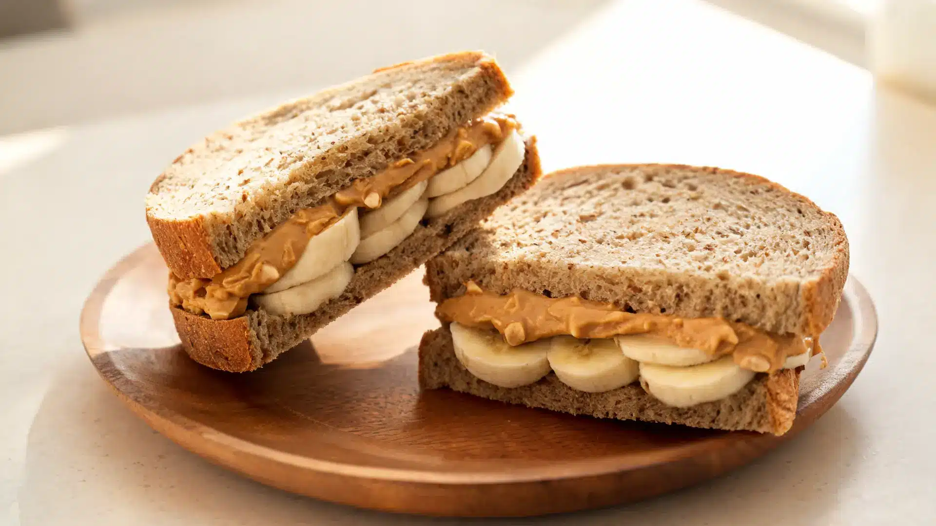 healthy whole wheat peanut butter banana sandwich with banana slices and natural peanut butter on rustic plate