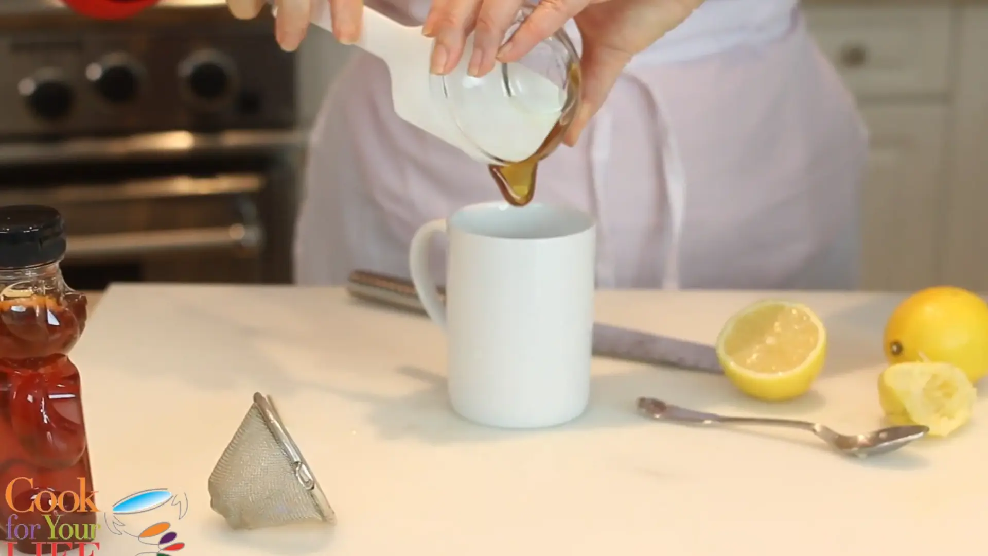 honey being added into warm lemon water in cup for natural sweetening