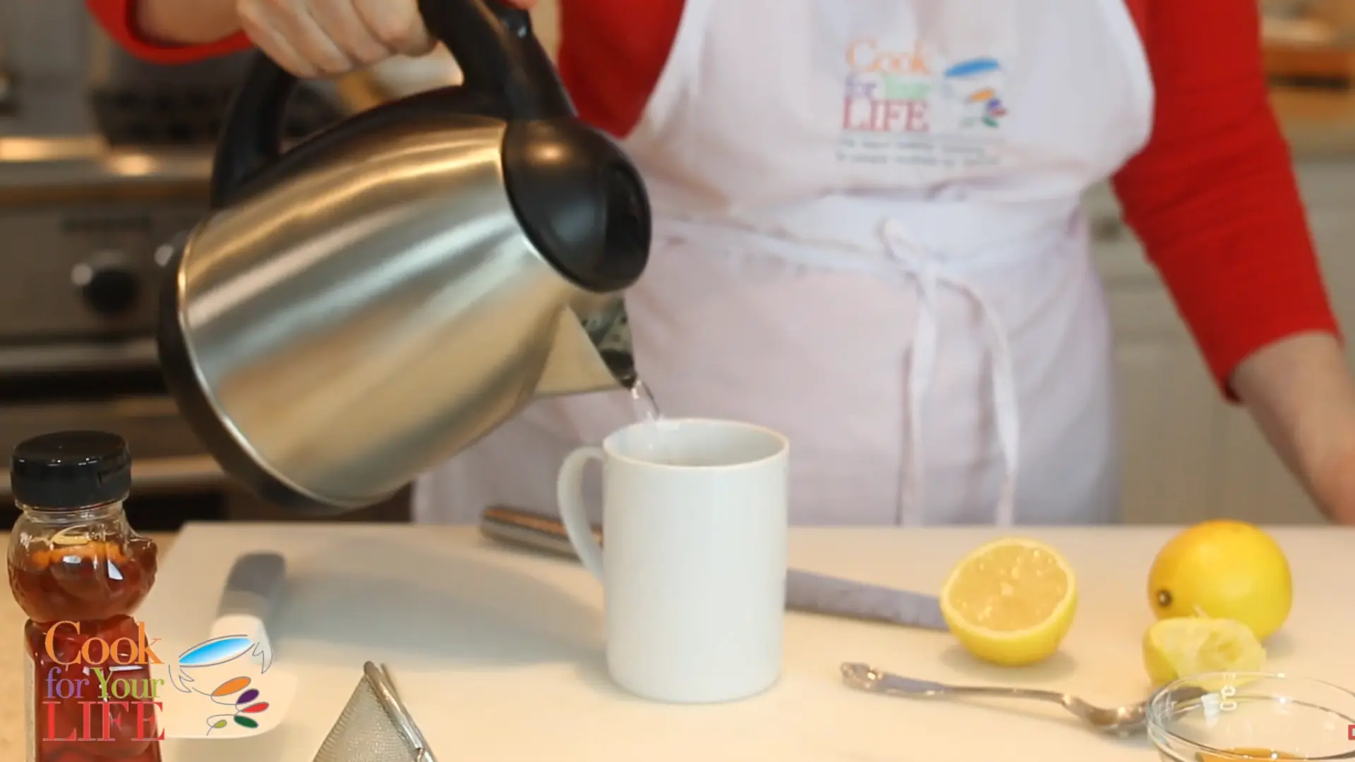hot water being poured into cup with fresh lemon juice to make warm lemon drink