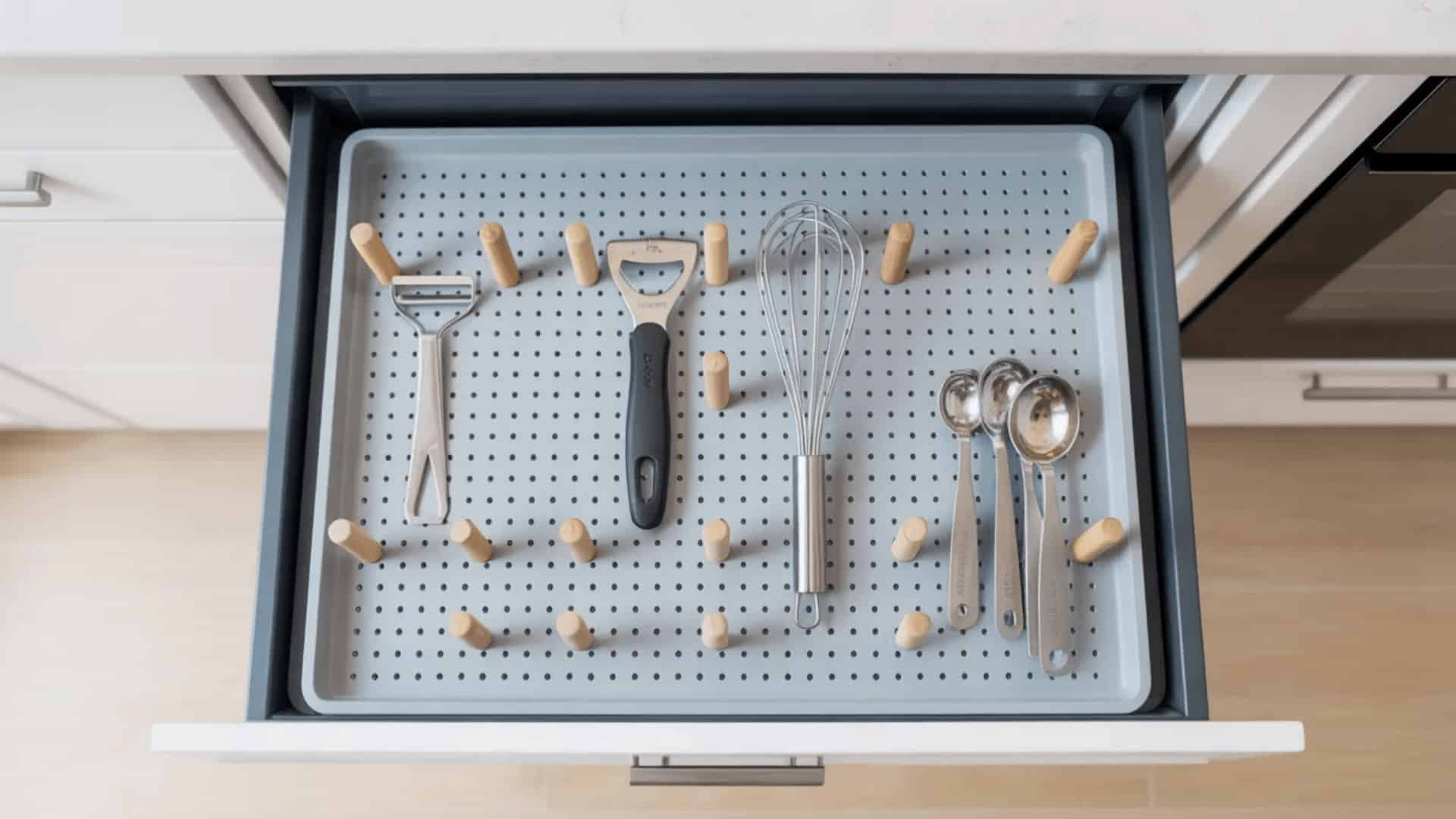 kitchen drawer with grey pegboard insert and small pegs creating custom compartments holding various small kitchen tools