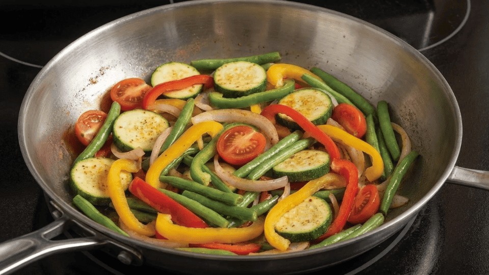 mixed vegetables sautéed in a stainless steel pan on a stovetop showing how the pan handles everyday cooking