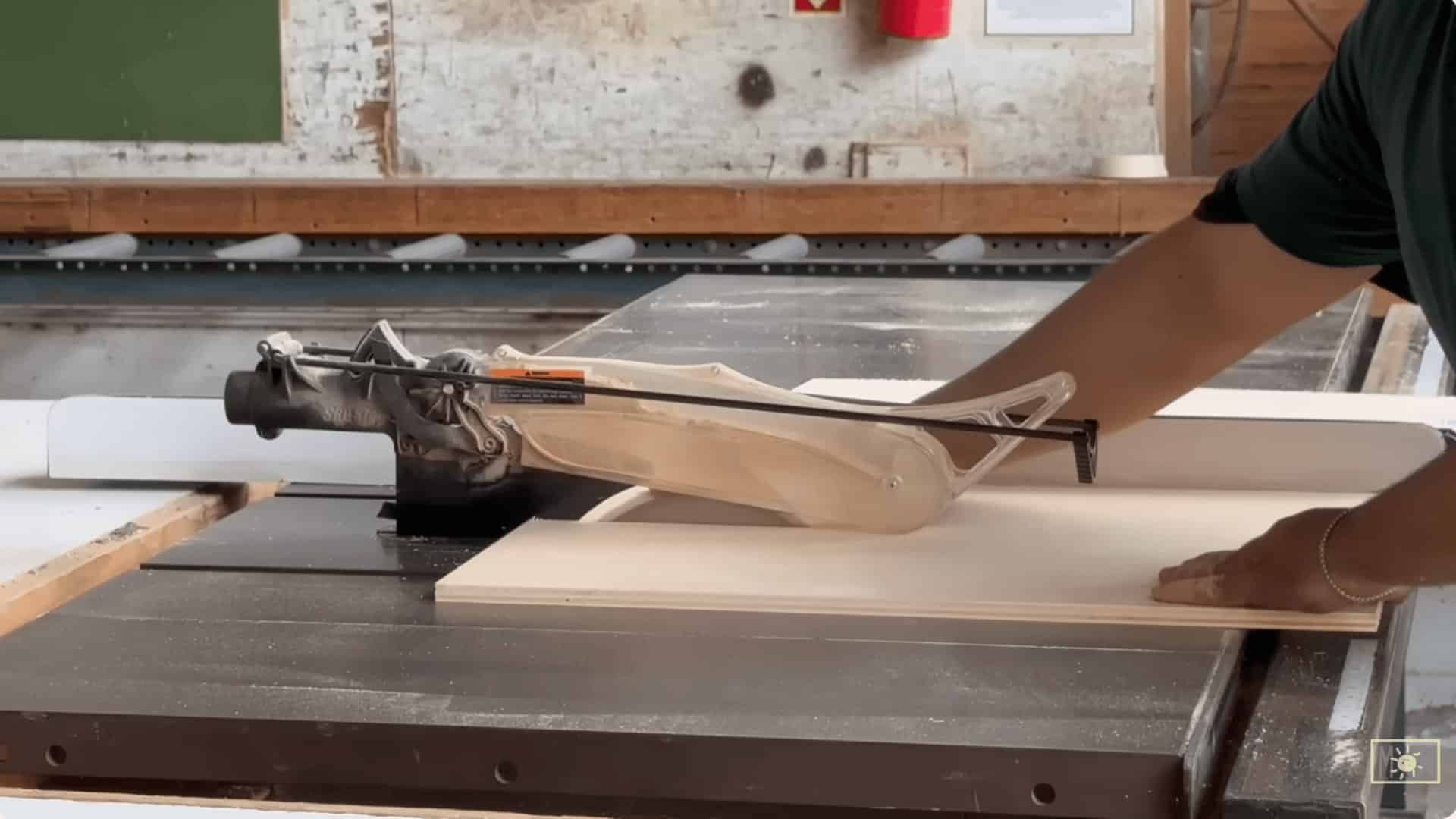 person cutting plywood board on a table saw to create narrow strips for drawer divider pieces in a workshop