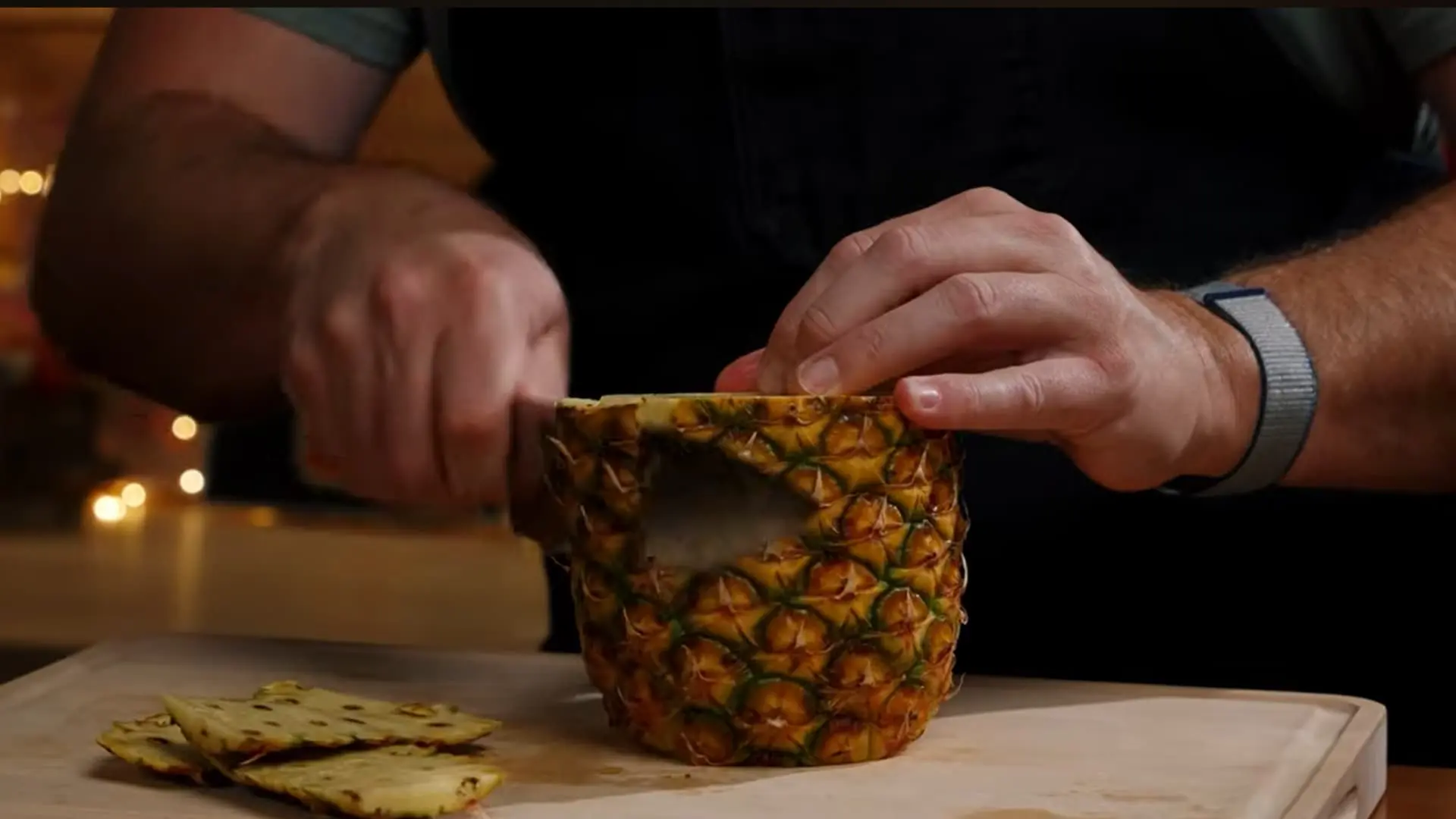 pineapple being peeled with a sharp knife removing outer skin and eyes for fresh juice preparation