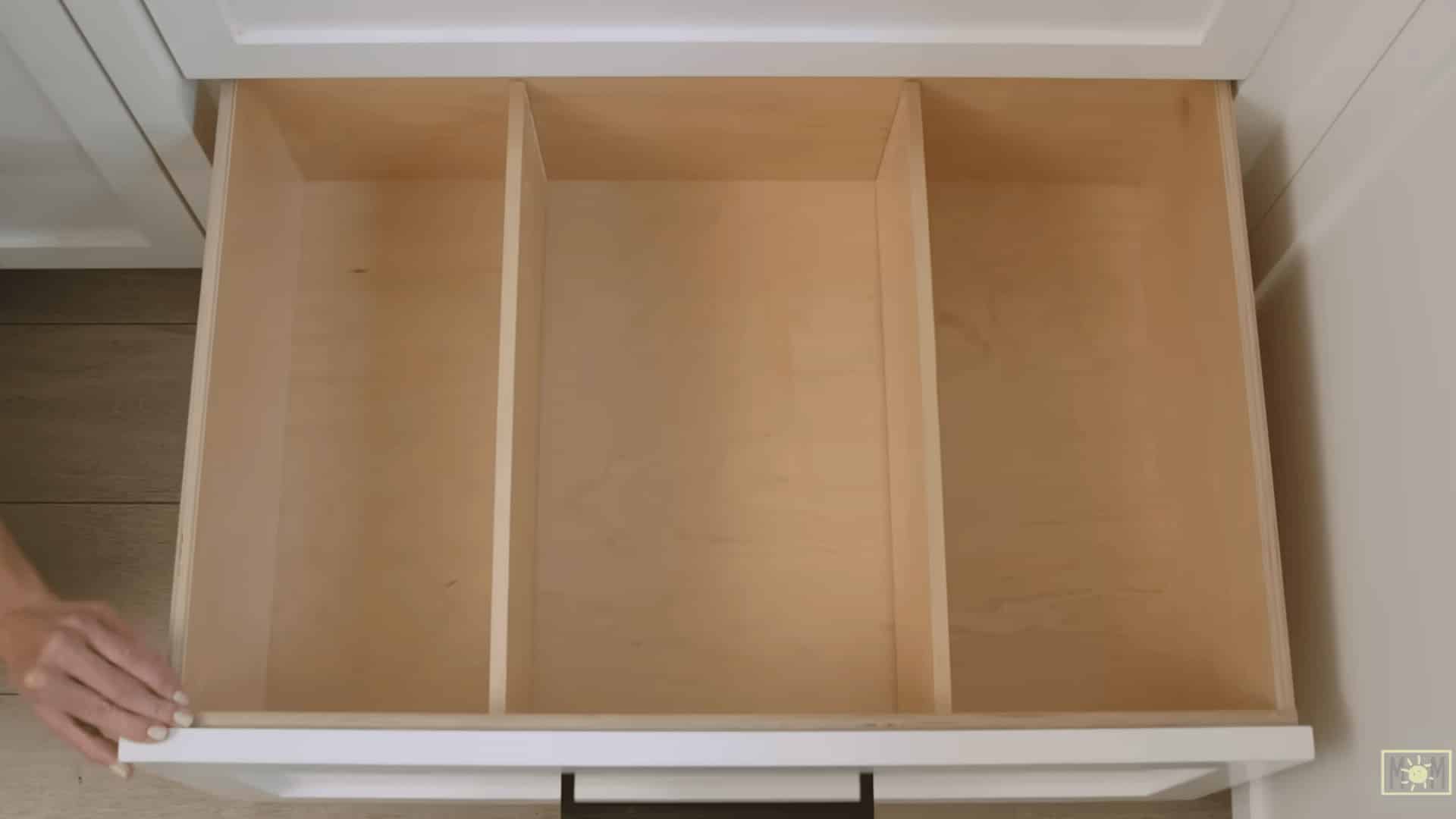 top view of a kitchen drawer with newly installed plywood dividers creating separate sections for organized storage