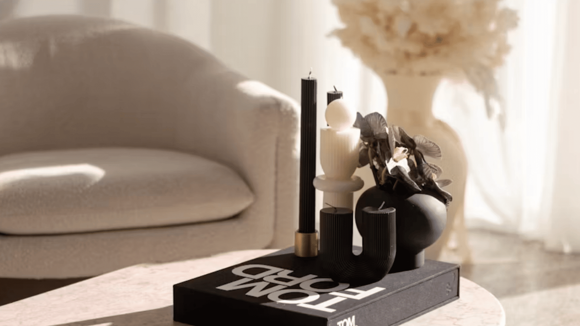 black and white candles with decorative vase displayed on a tom ford book atop a modern coffee table