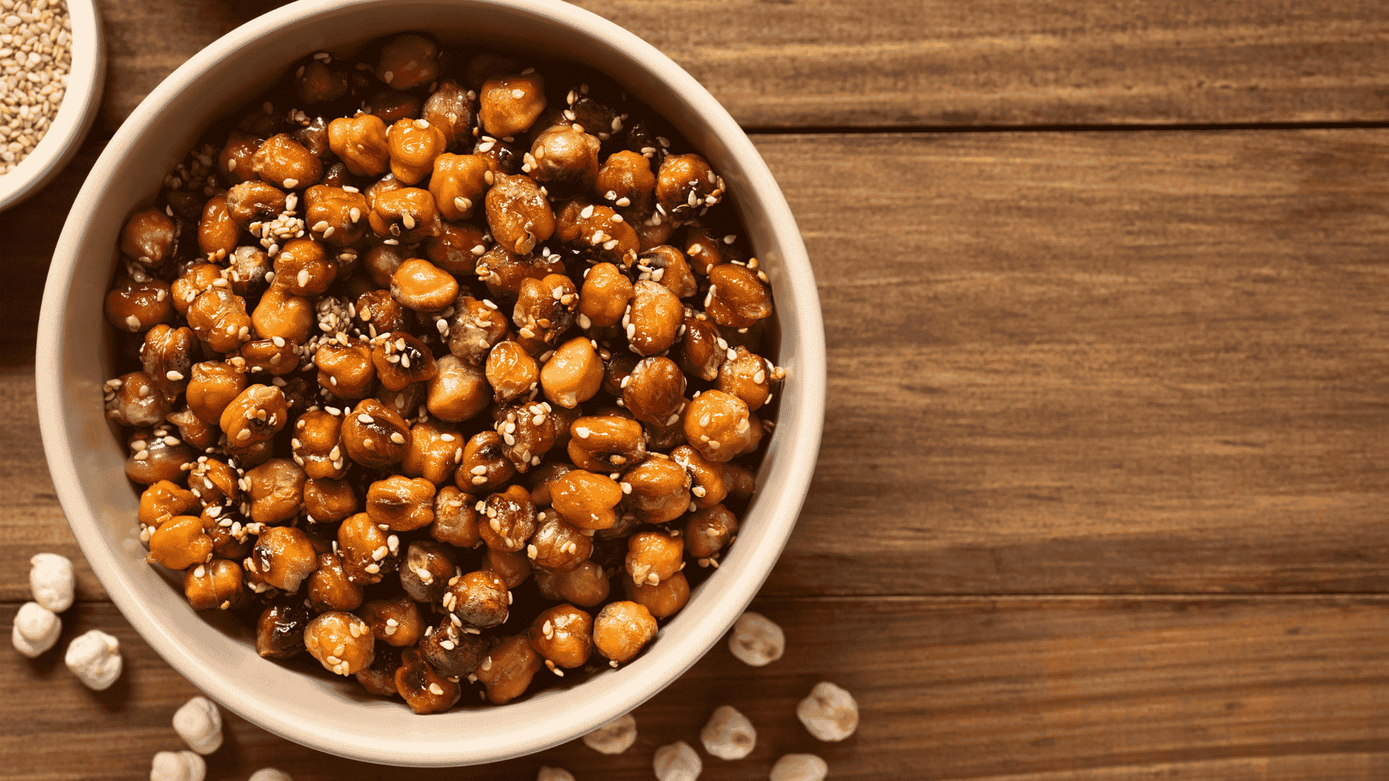 bowl of roasted chickpeas with sesame seeds on wooden table offering a healthy crunchy snack
