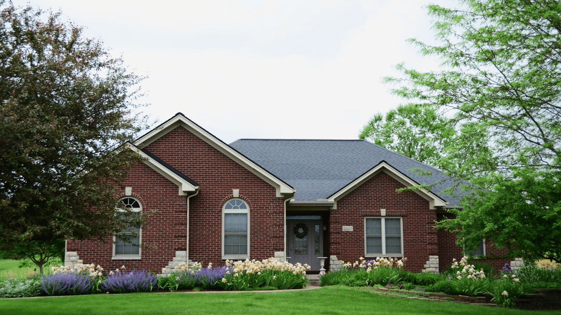 brick building facade with tall arched windows and sunlight shining through nearby trees