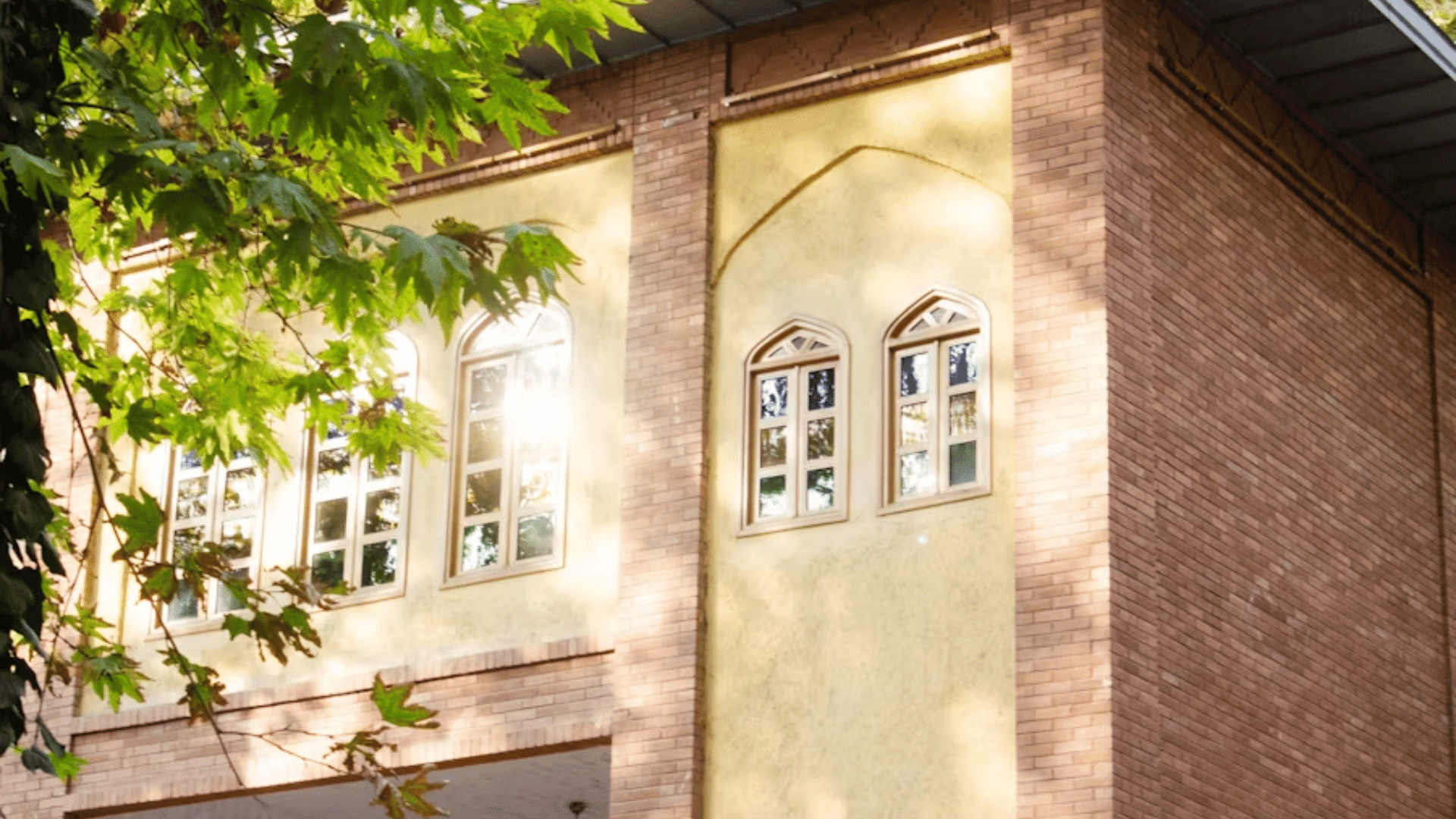 brick house exterior with blue roof white trim windows and plants beside the entrance at dusk