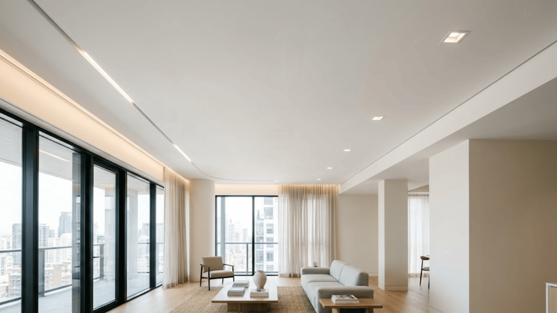 bright modern living room with white sofa low coffee table floor to ceiling windows and soft curtains overlooking city skyline
