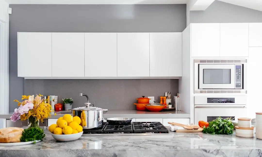 Modern kitchen with stainless steel appliances, white cabinets, and colorful cookware on the counter