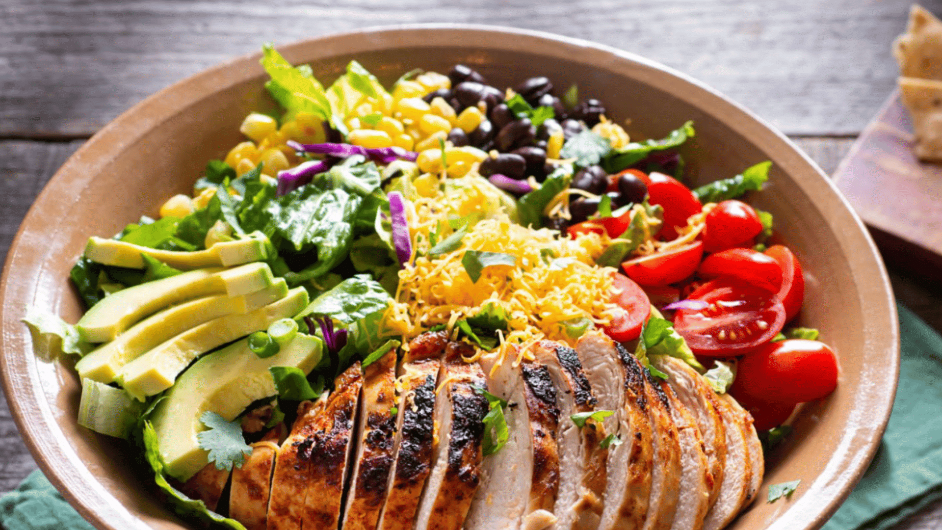chicken salad bowl with avocado tomatoes beans greens and shredded cheese