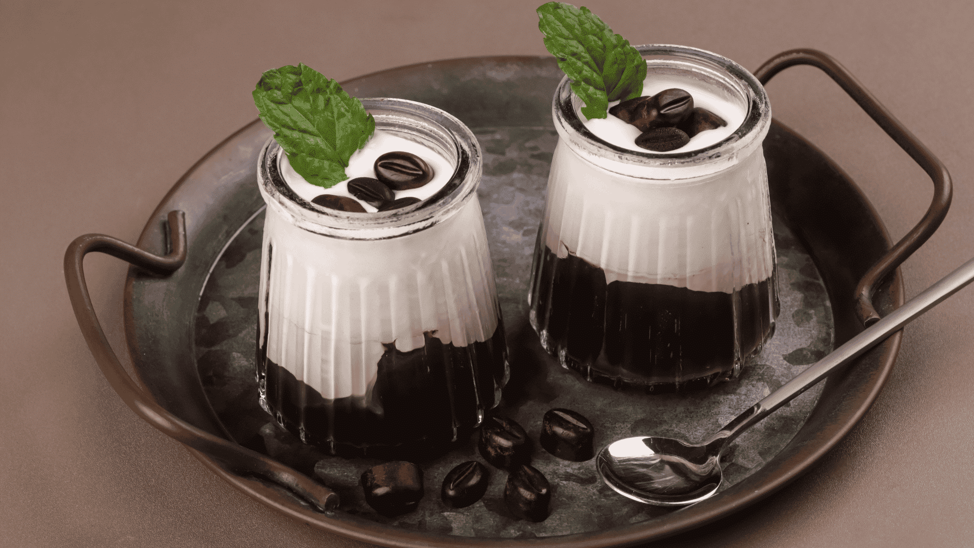 coffee jelly dessert layered with creamy milk topping and coffee beans served in glass cups with fresh mint