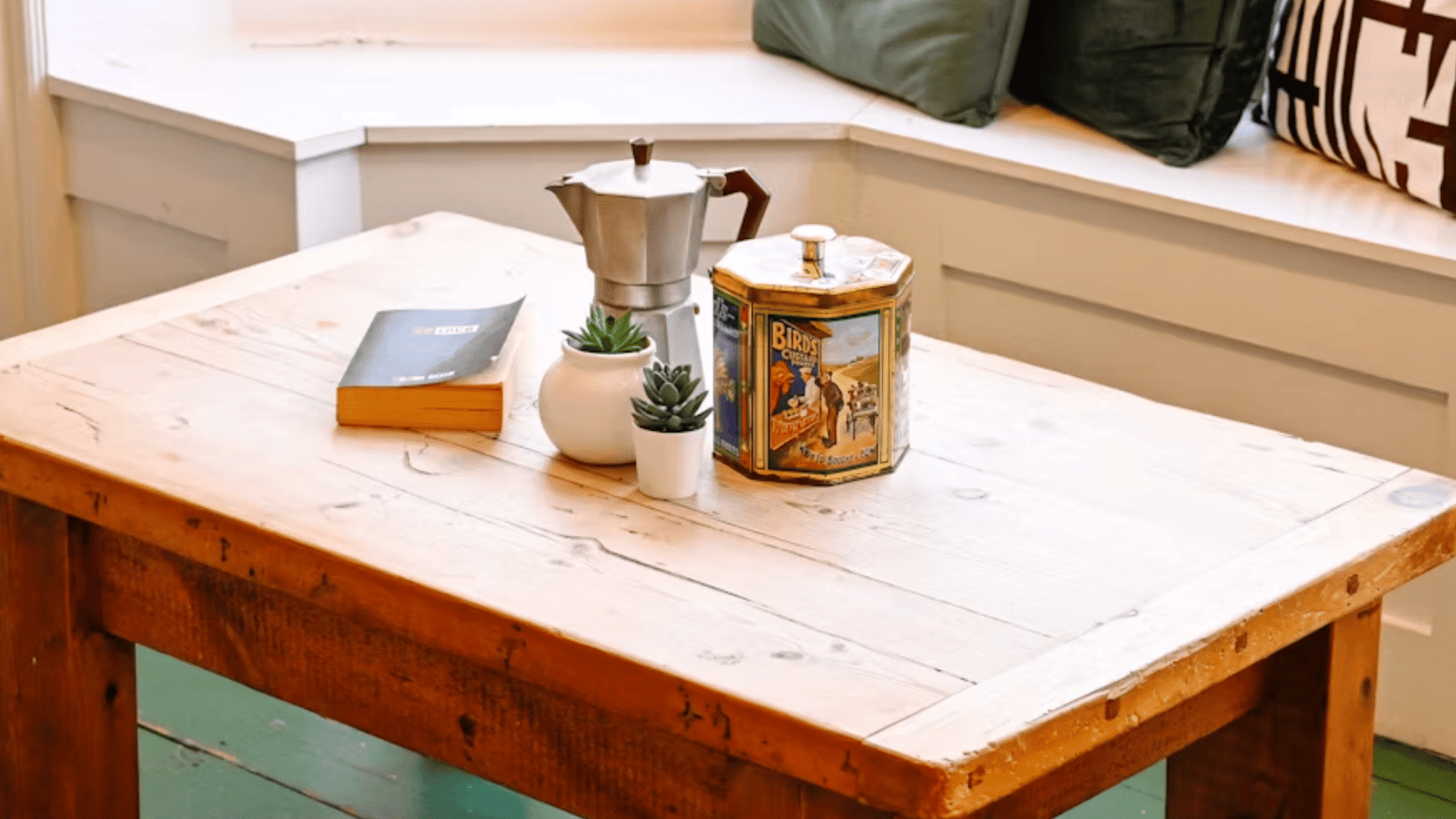coffee maker with decorative tin books and small potted plants arranged on a rustic wooden coffee table