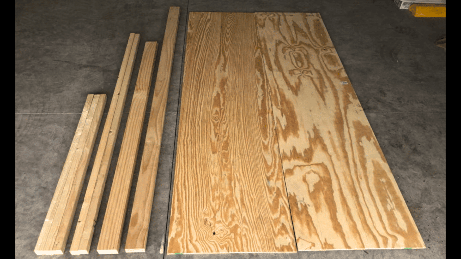 cut lumber pieces and plywood boards prepared for building a diy upholstered headboard frame