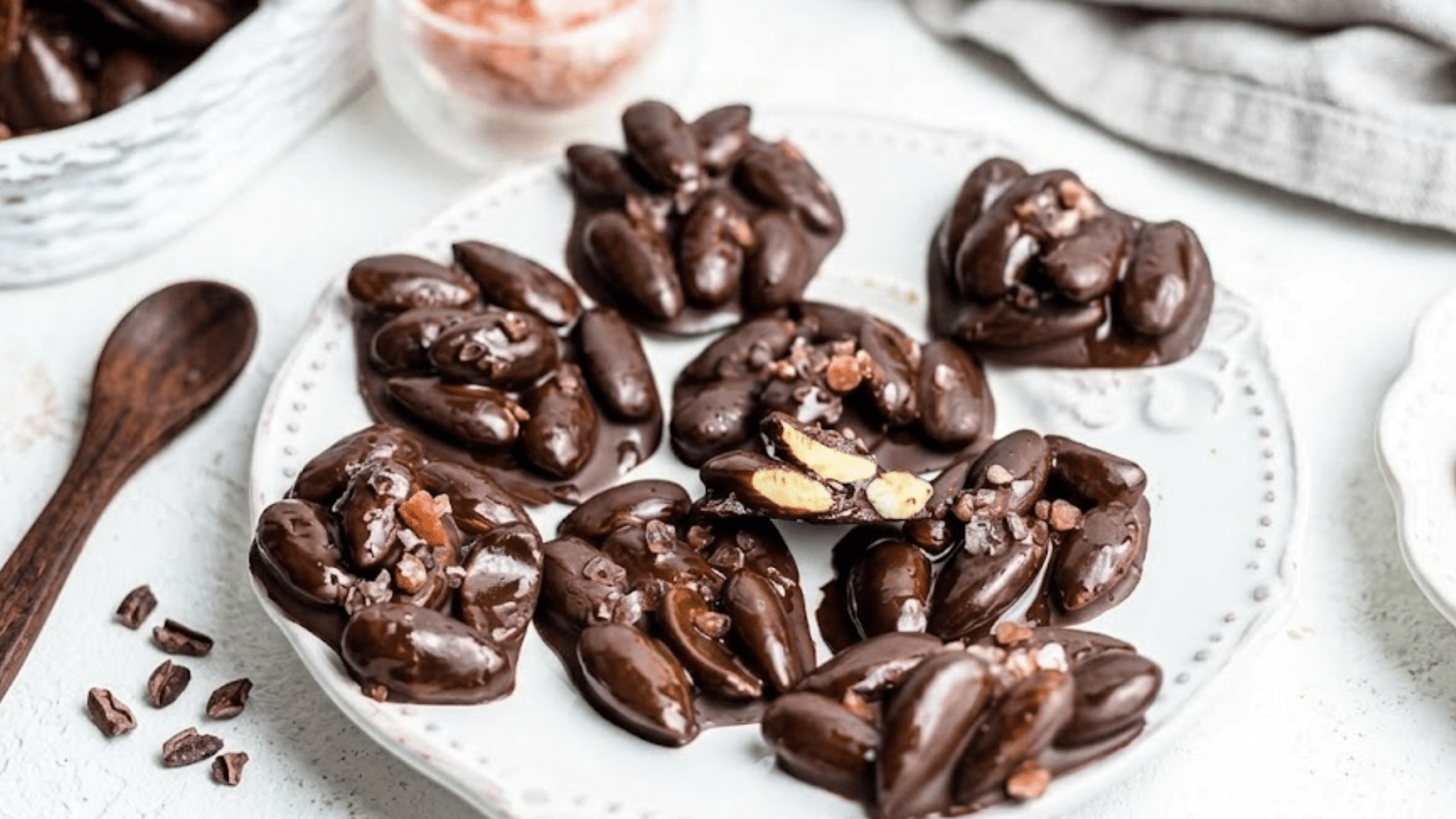 dark chocolate clusters with whole almonds topped with coarse salt arranged on a plate as a rich homemade snack