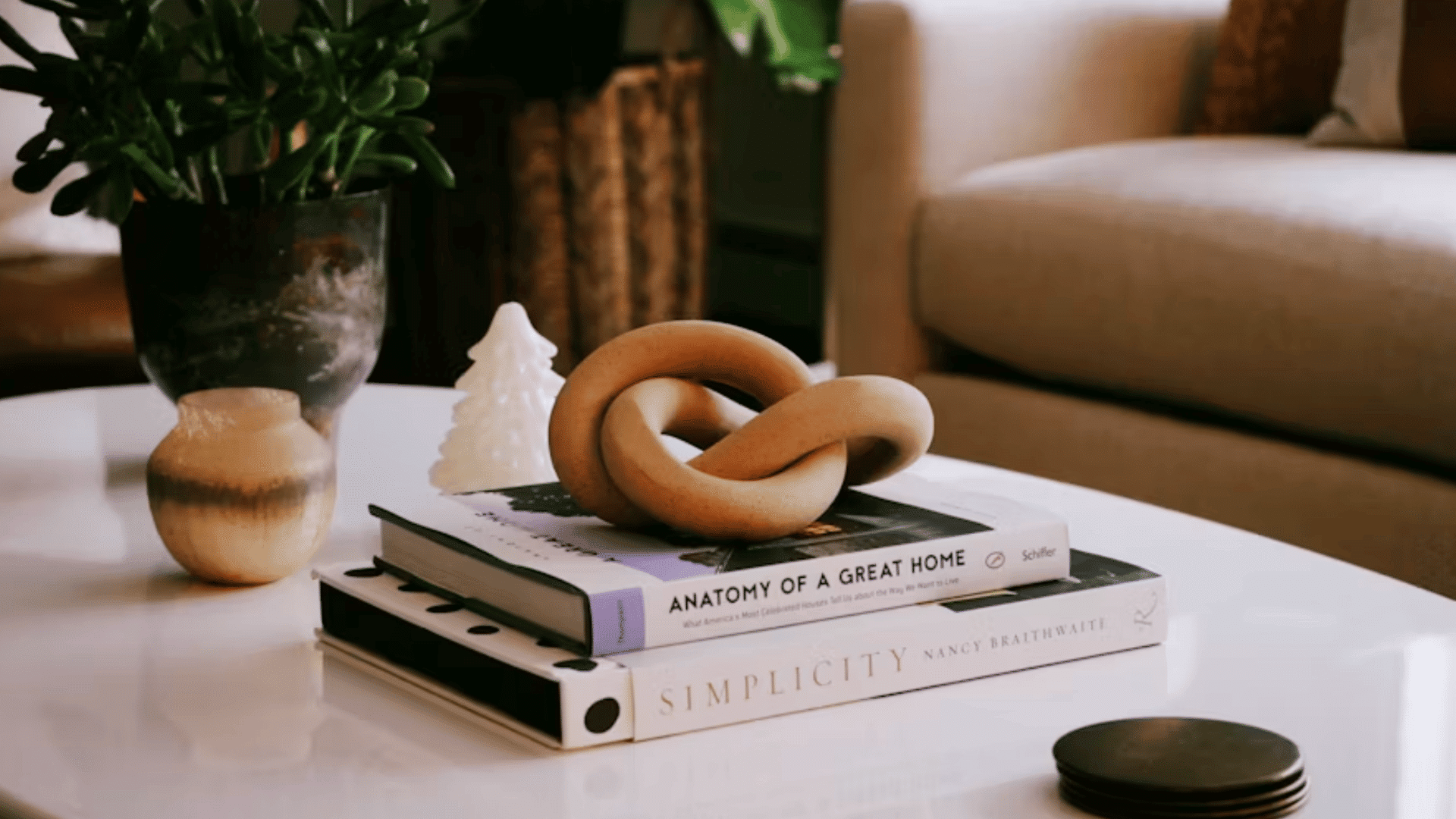 decorative knot sculpture on stacked books with potted plants and ceramic accents on a modern coffee table