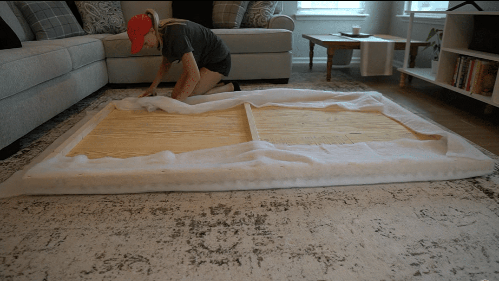 foam padbatting material stretched over the headboard frame before securing the edgesding placed on the plywood surface for a soft upholstered headboard layer