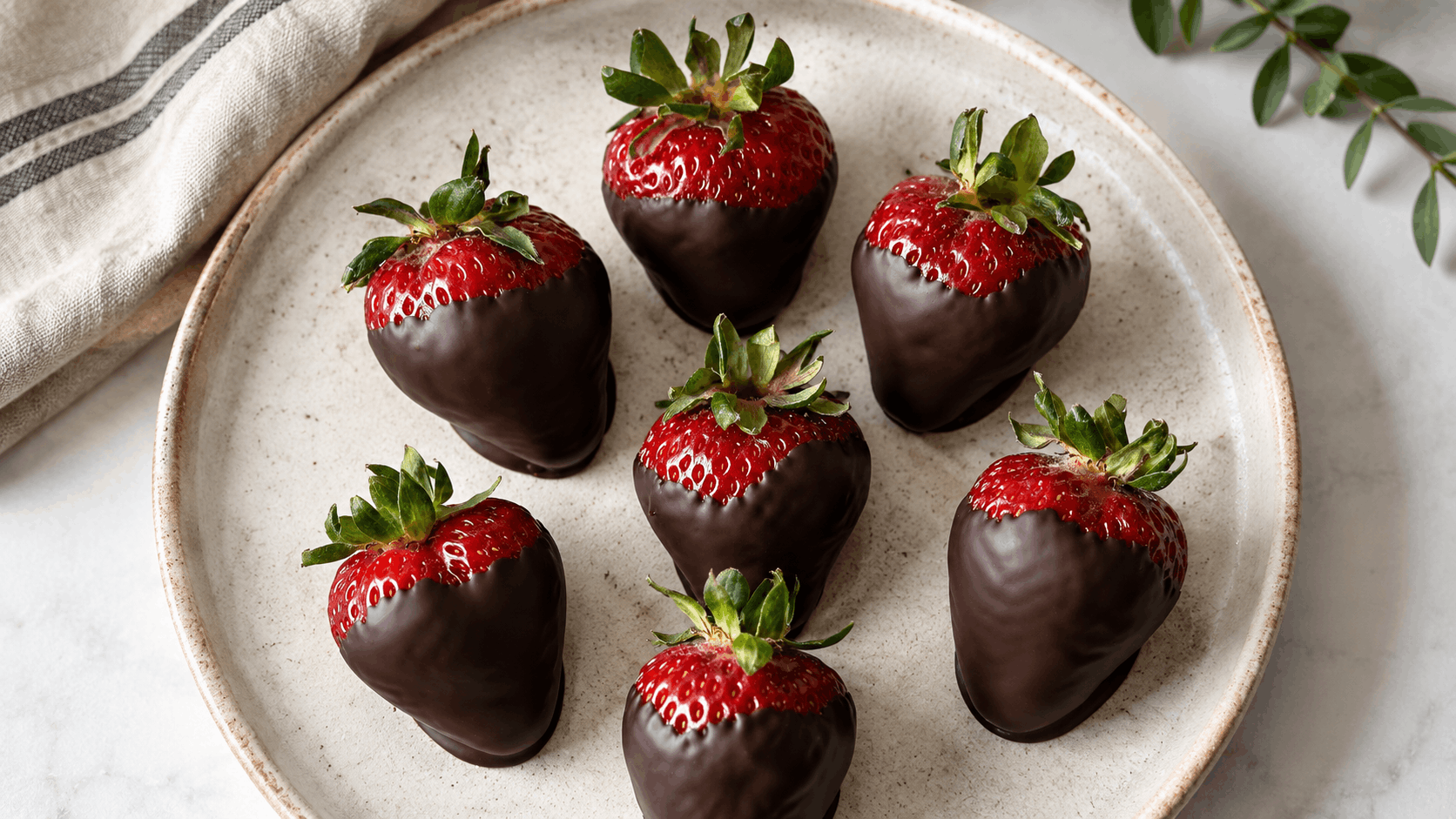 fresh strawberries dipped in smooth dark chocolate and arranged on a ceramic plate with a glossy homemade finish