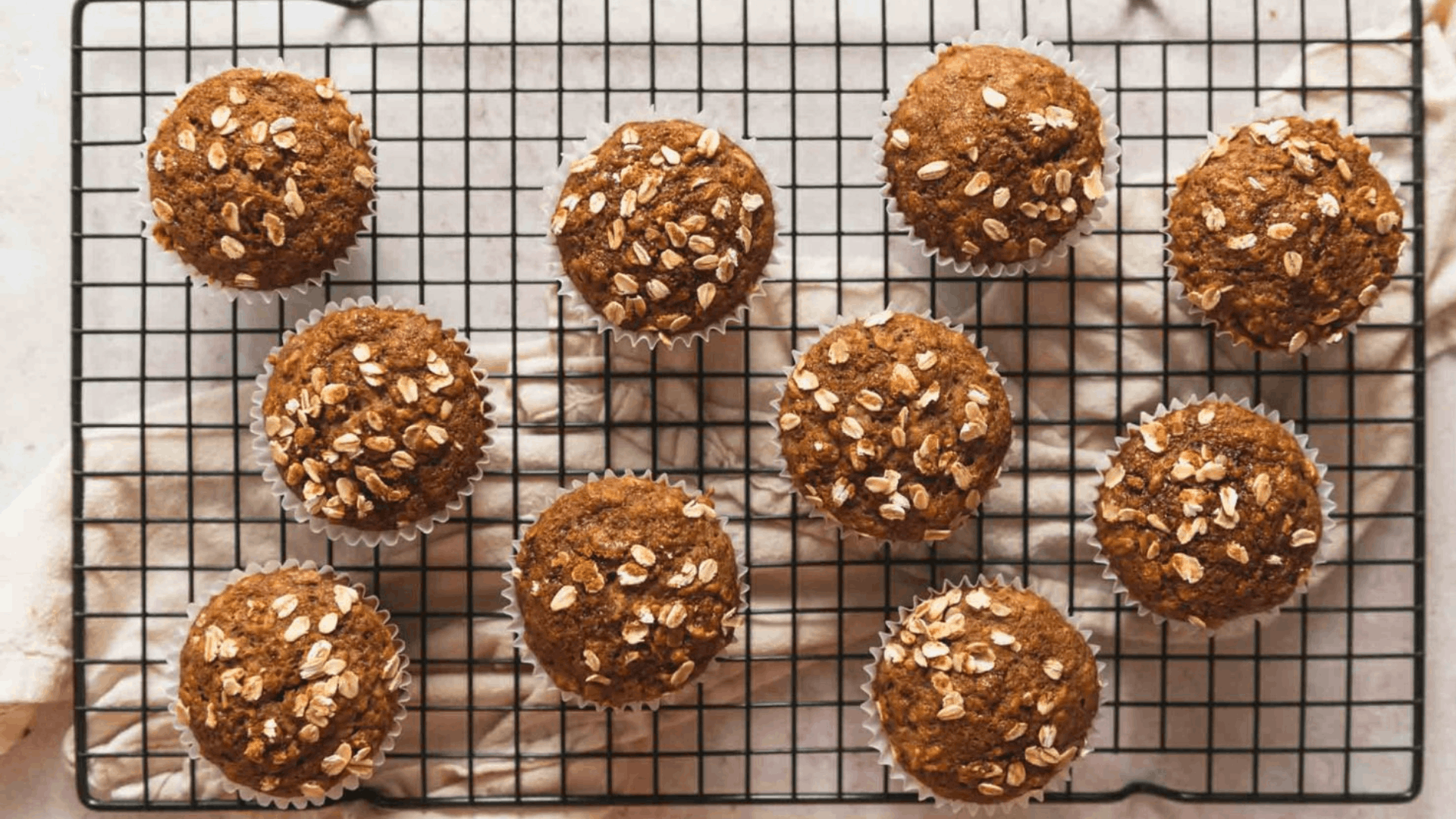 freshly baked oat topped muffins cooling on a wire rack over a kitchen towel ready to enjoy as a wholesome homemade snack (1)
