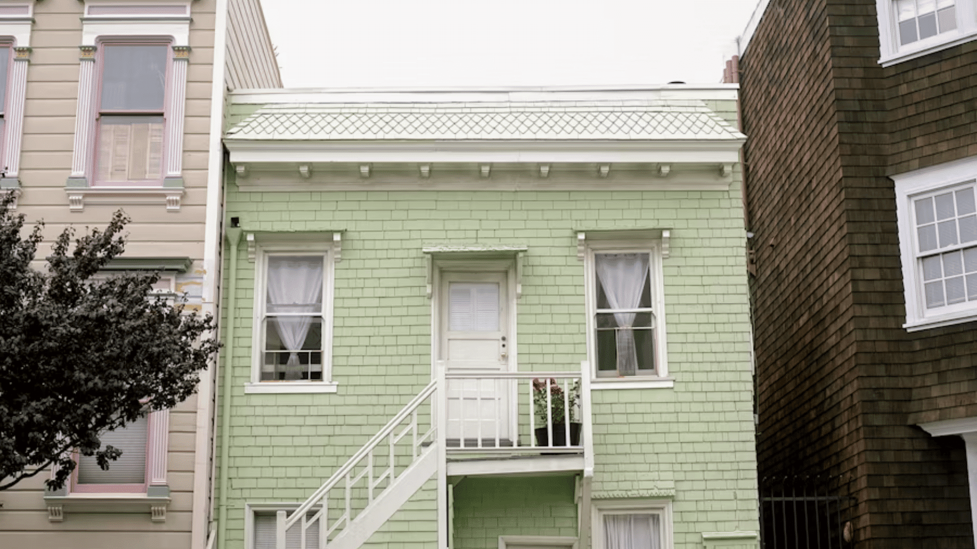 light green wooden house with raised entrance stairs and neighboring homes on both sides