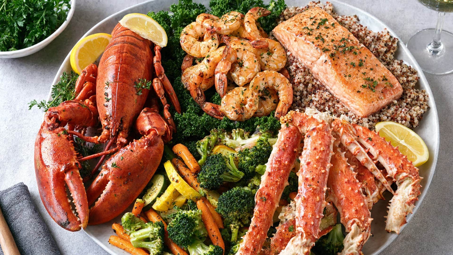 lobster, shrimp, salmon, and crab seafood platter with vegetables and grains showing a balanced meal