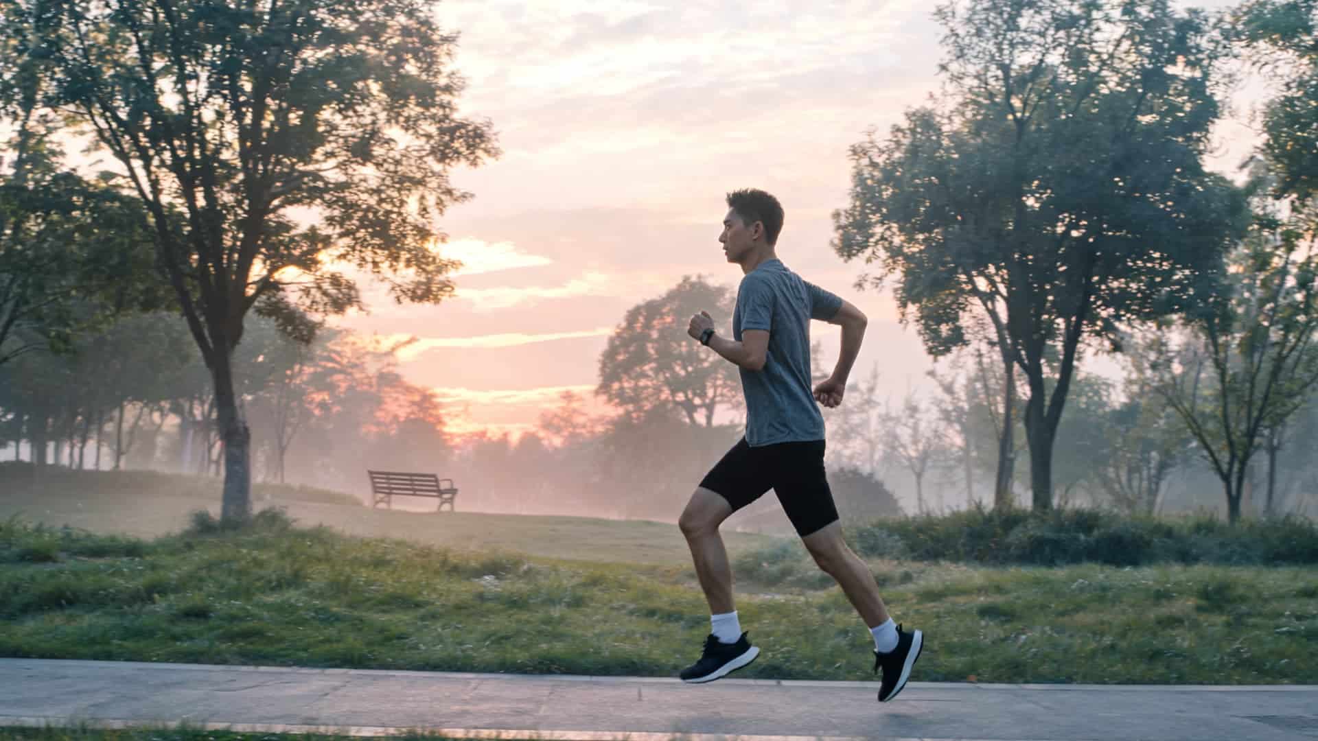 man jogging on a park pathway at sunrise with trees and soft mist creating a calm outdoor fitness scene (1)