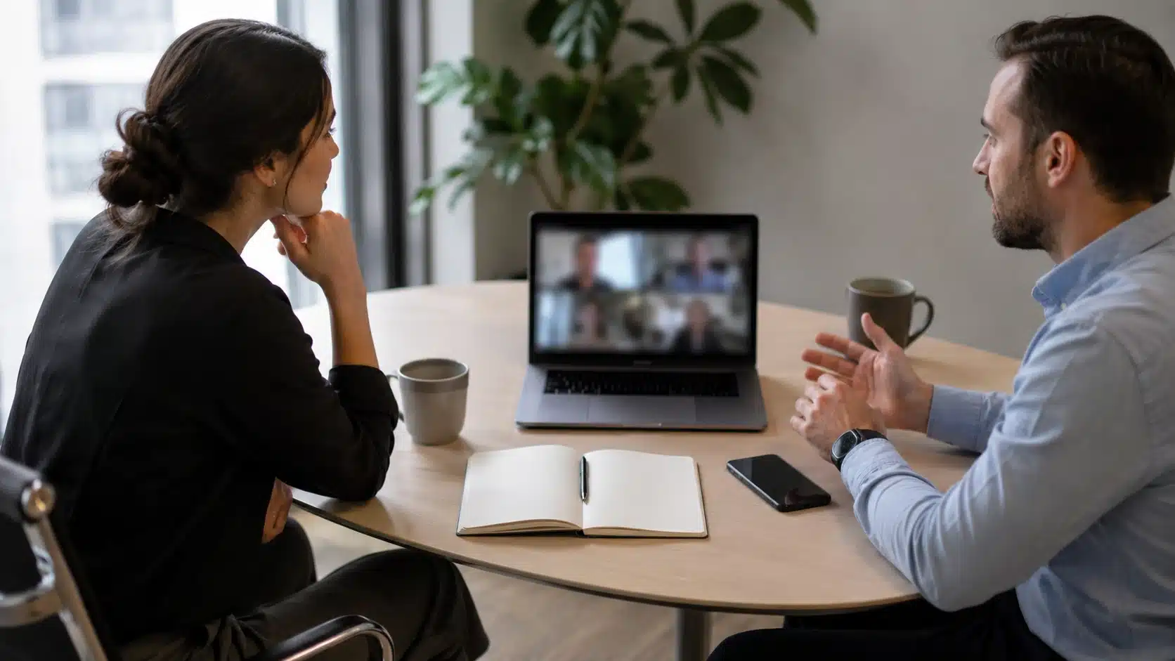 meeting table with phone face down and open notebook showing active listening during workplace conversation