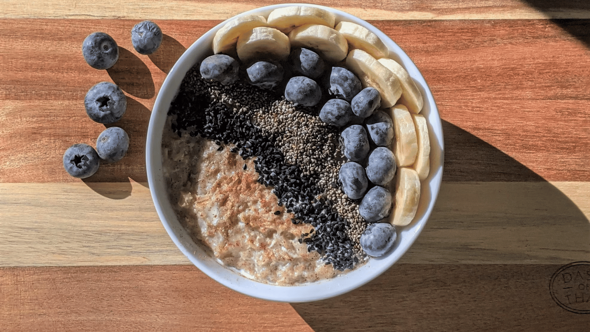 oatmeal bowl topped with blueberries banana slices chia seeds and black seeds