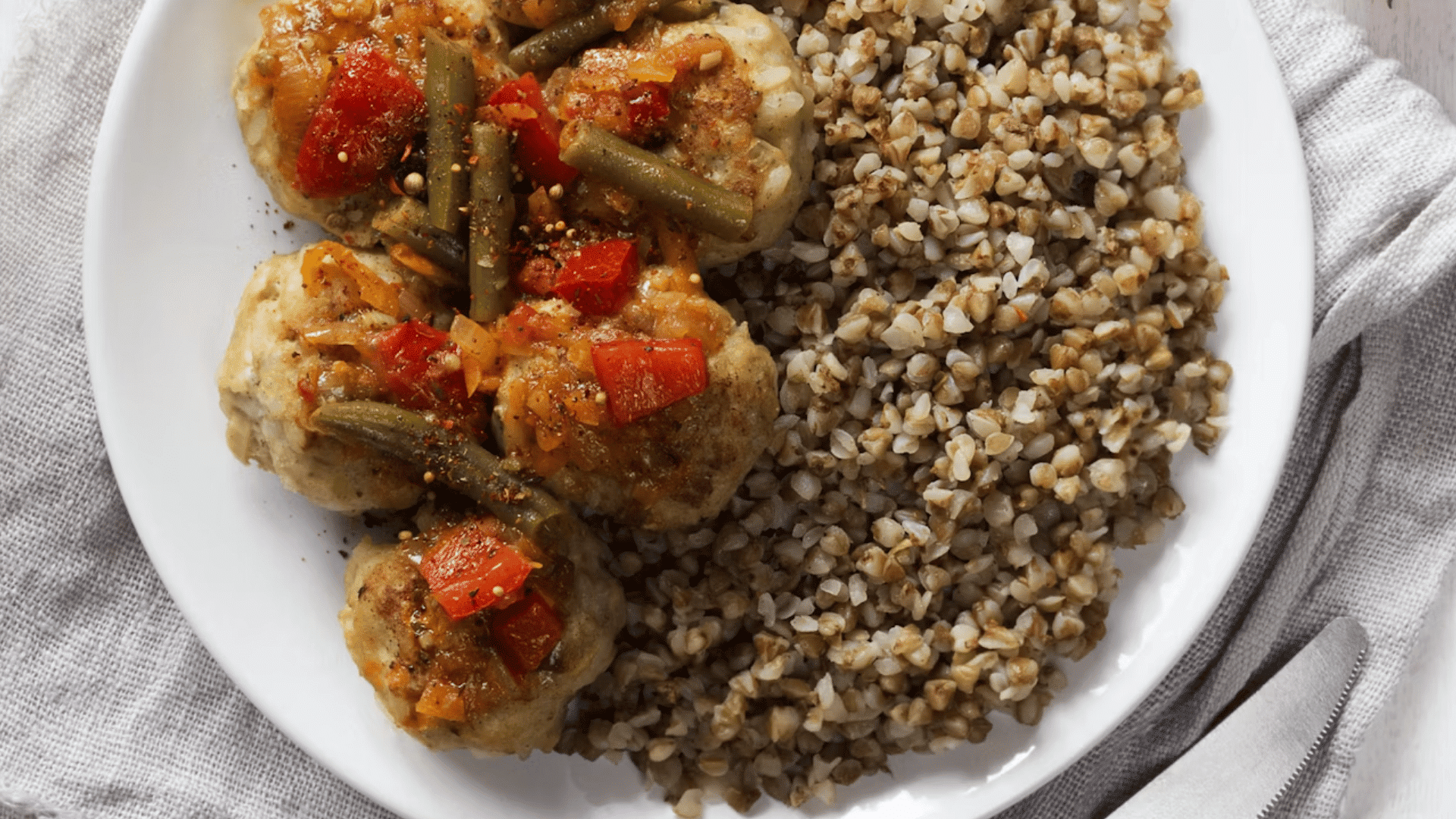 plate of meatballs with buckwheat grains vegetables and tomato sauce