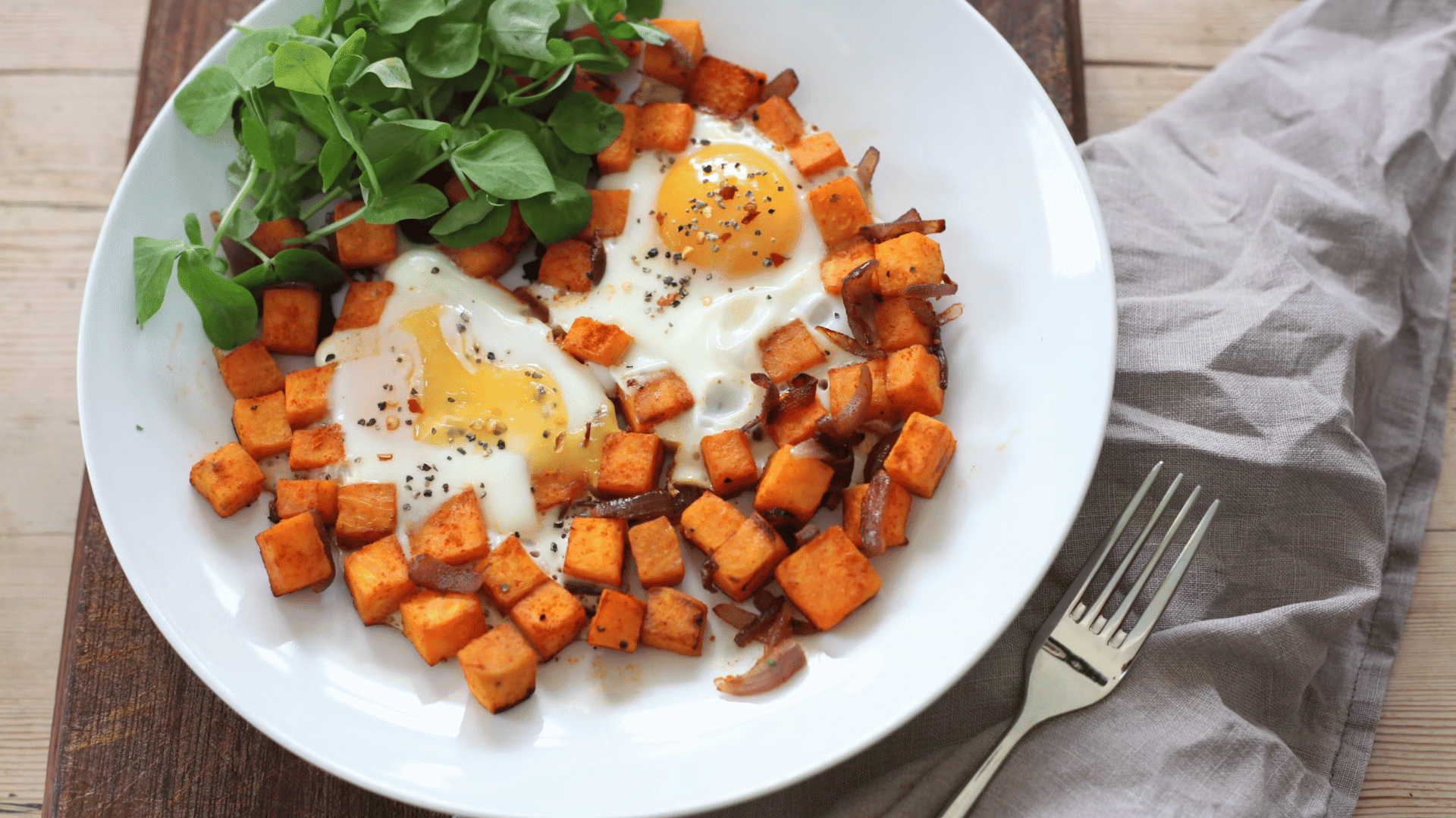 plate of roasted sweet potatoes with fried eggs greens and seasonings