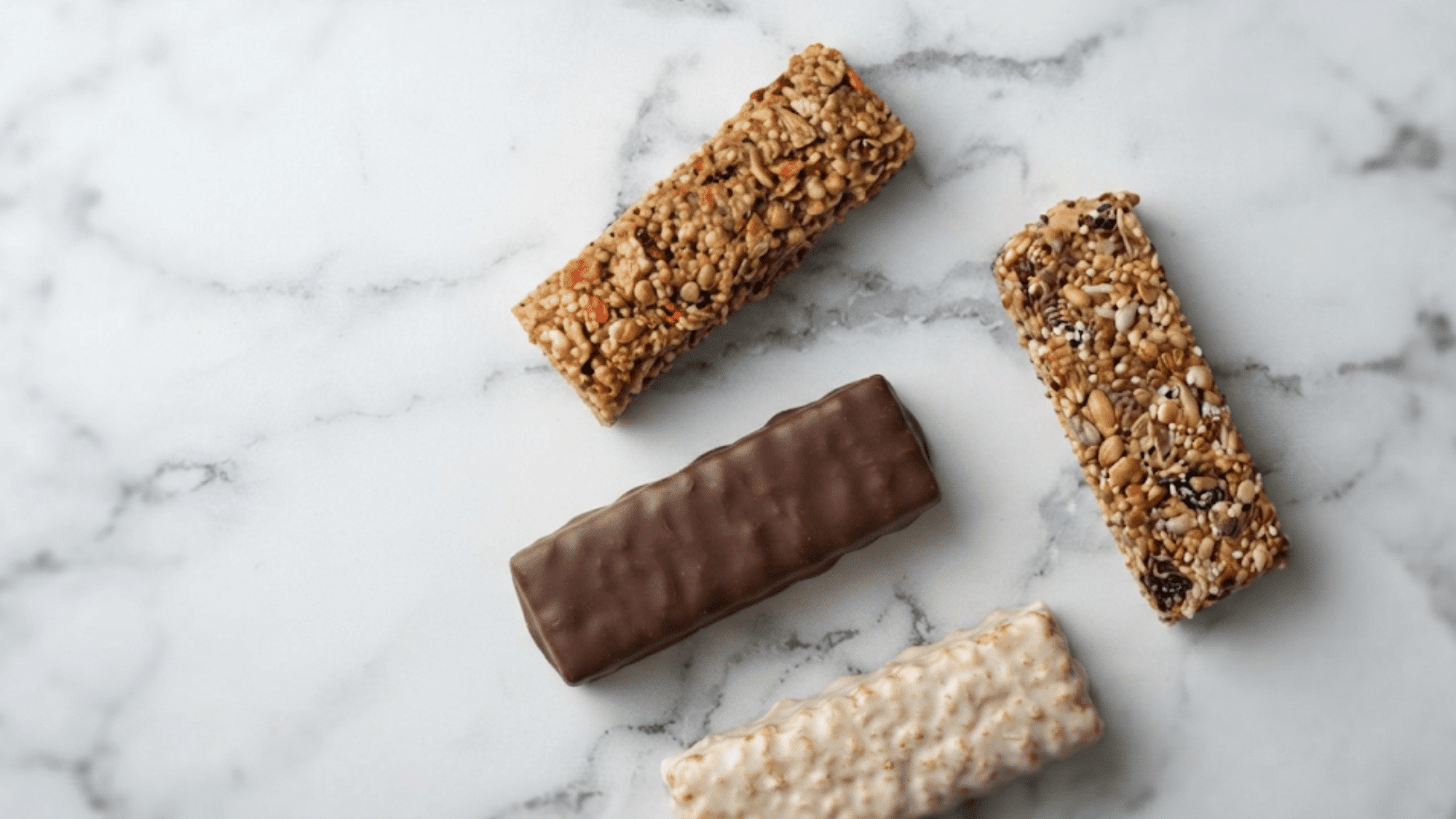 protein bars with different coatings and seeds arranged on a marble surface for a high protein snack choice