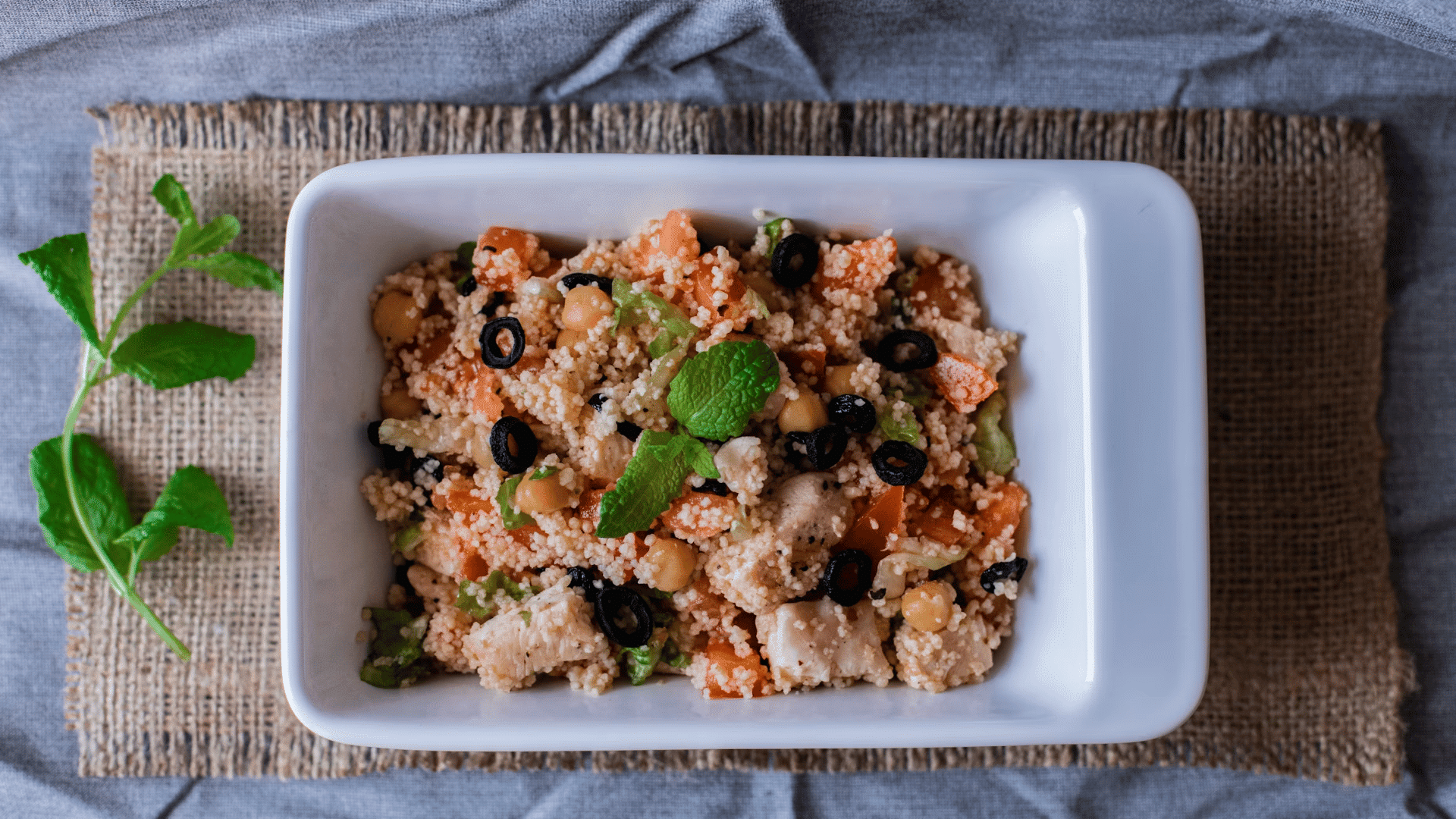 rectangular dish filled with couscous chicken vegetables chickpeas and black olives