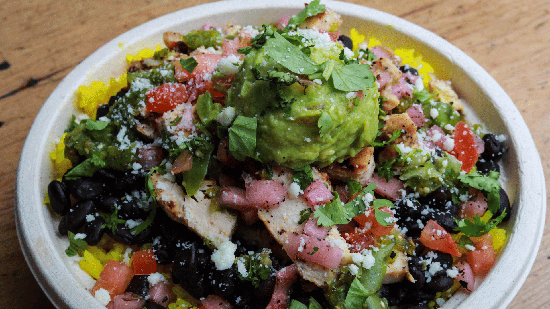 rice bowl topped with grilled chicken avocado beans salsa and fresh cilantro