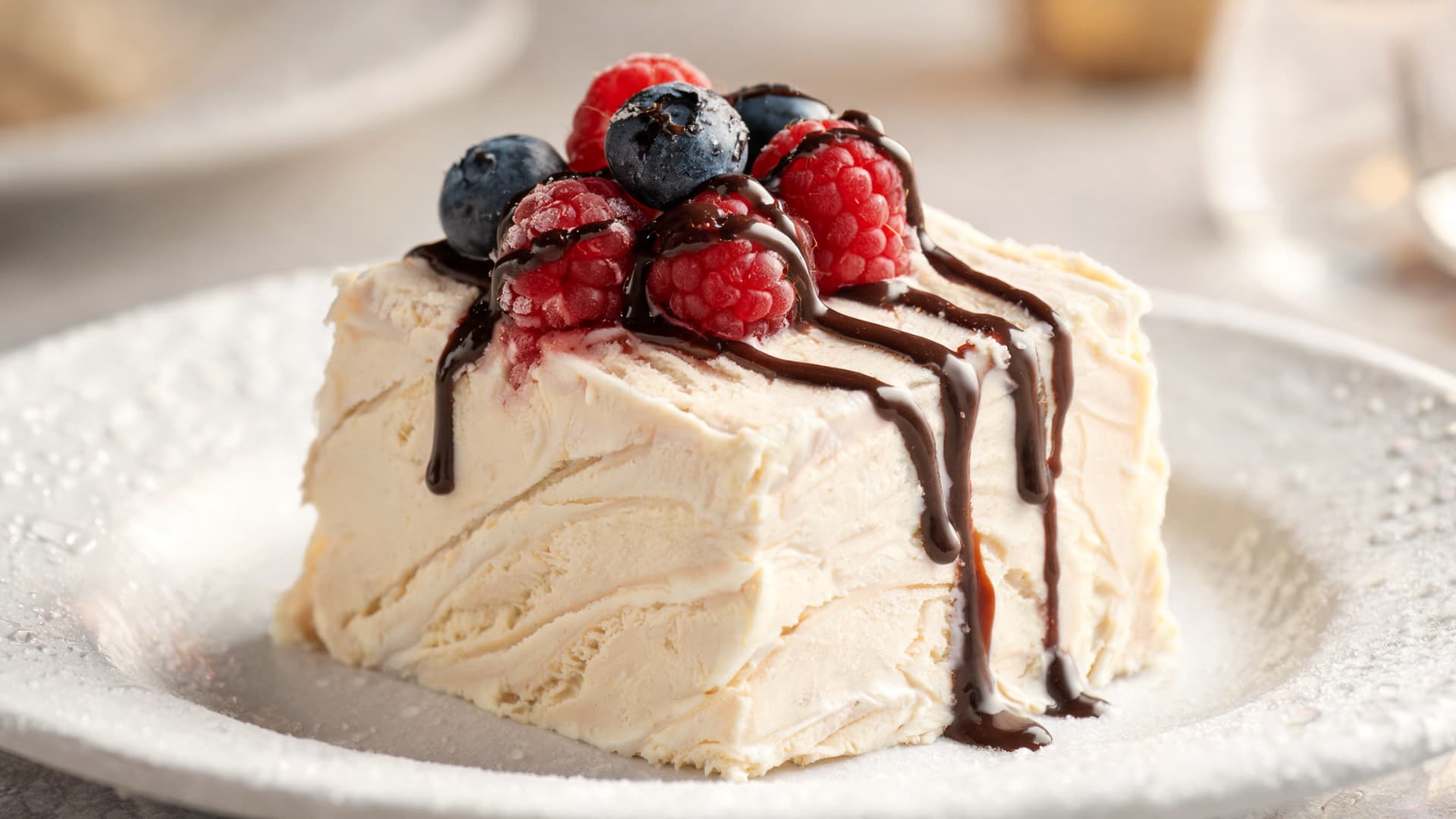semifreddo frozen creamy dessert slice topped with berries and chocolate drizzle elegant plated