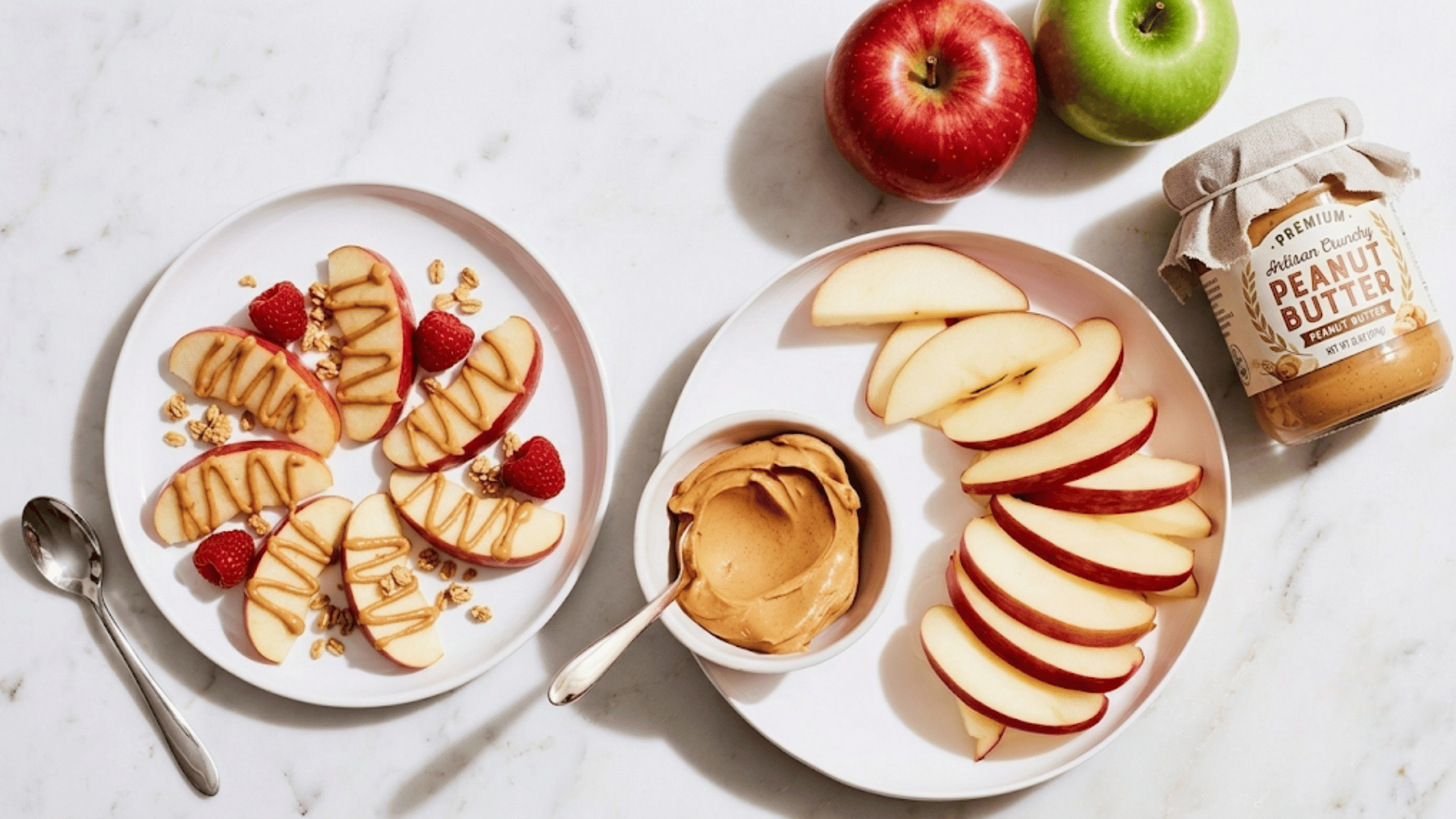 sliced apples arranged on plates with peanut butter drizzle dipping bowl raspberries granola whole apples and peanut butter jar