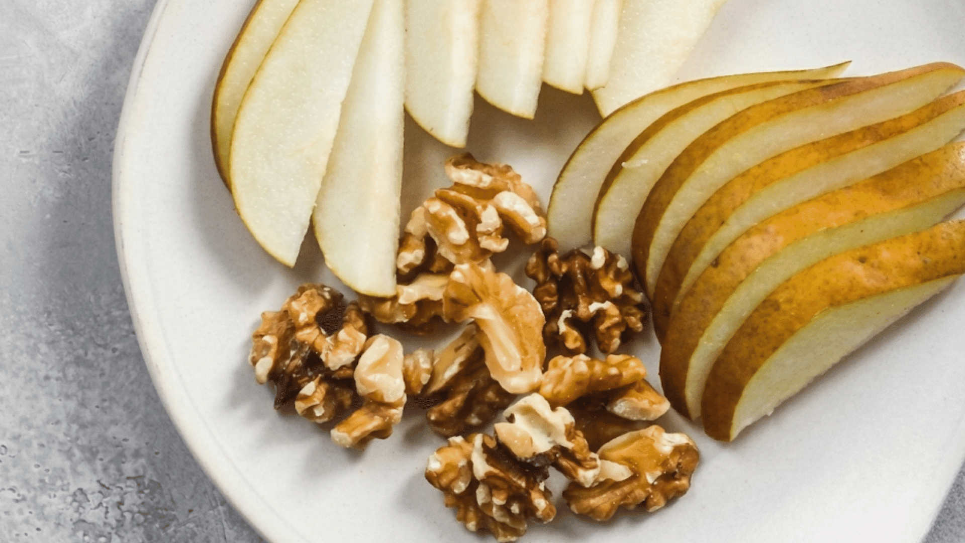 sliced pear arranged on a white plate with walnut halves creating a fresh nutritious snack ready to enjoy at any time